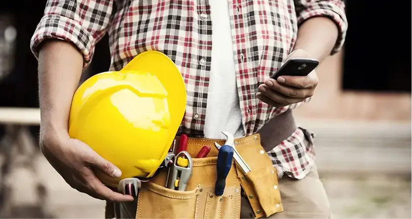 a person holding a yellow hard hat and a tool belt