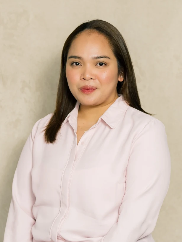 Professional portrait of a woman with straight brown hair, wearing a light pink blouse, against a neutral background.
