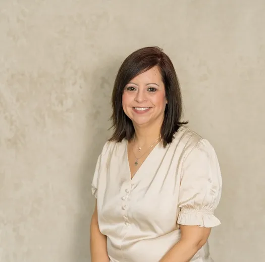 Professional portrait of a smiling woman with dark hair wearing a cream blouse.
