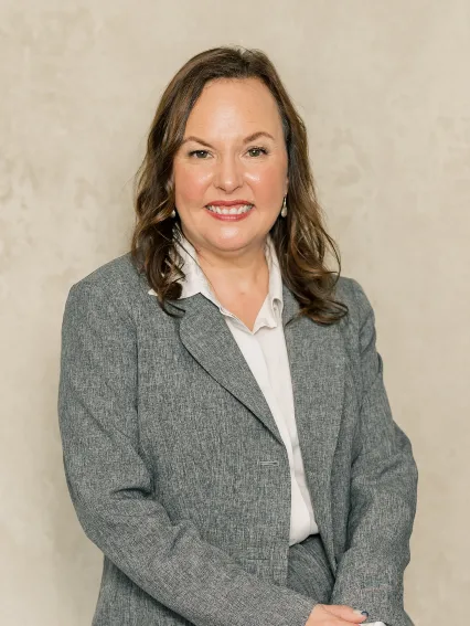 Professional portrait of a woman with brown hair wearing a gray suit and white blouse.