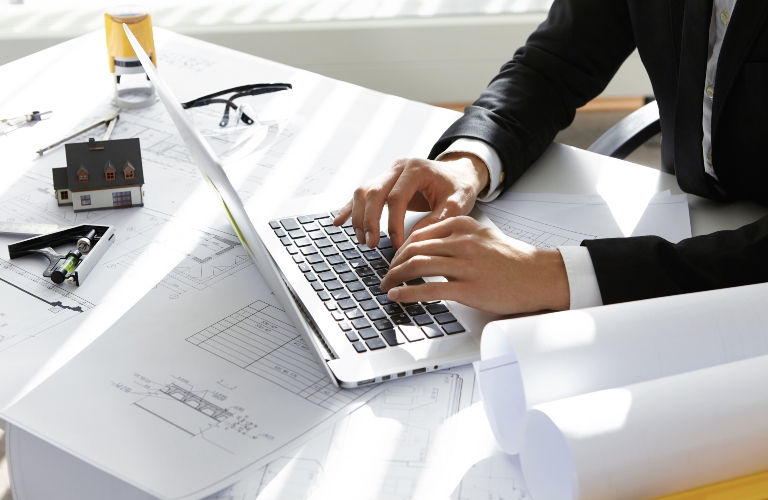 man in black suit is typing on laptop