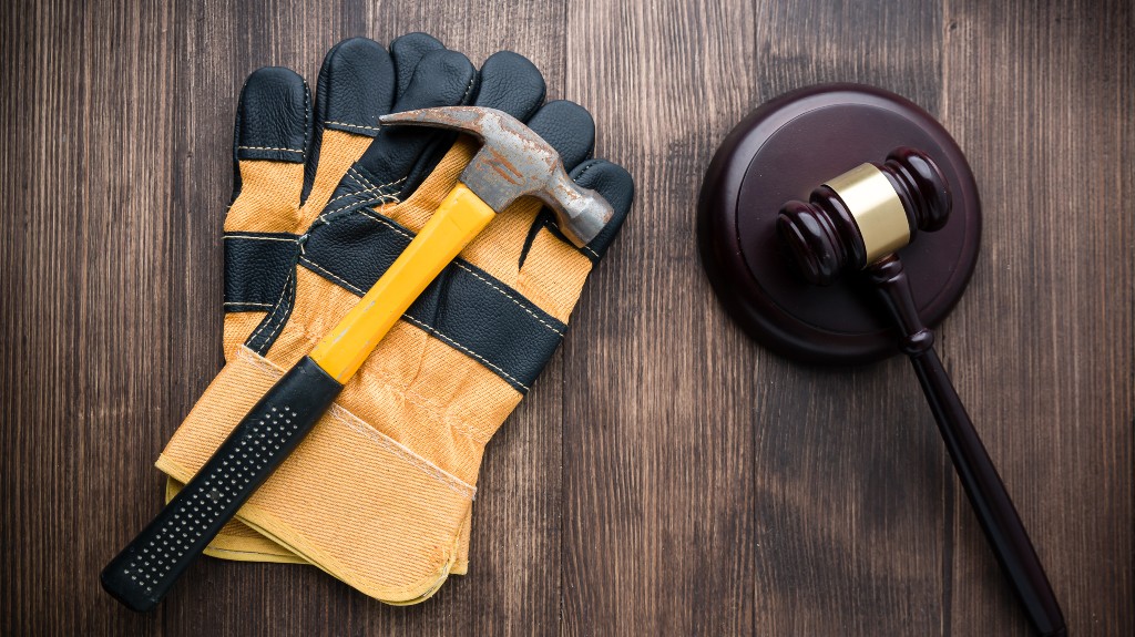wooden judge gavel and yellow construction gloves