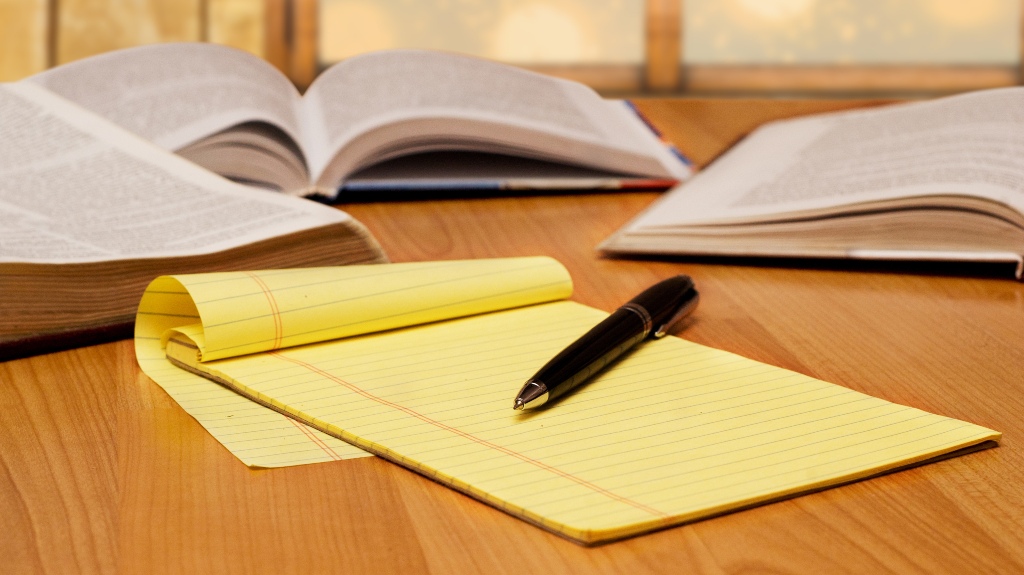 yellow legal pad on the table with books