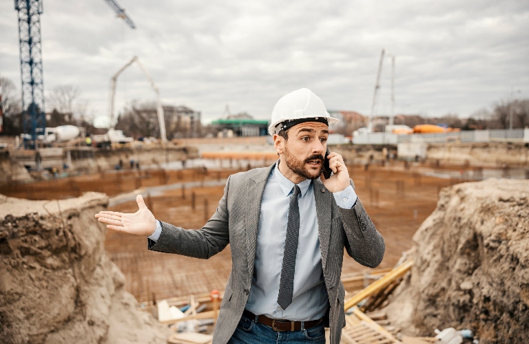 An angry architect is speaking on the phone with constructors