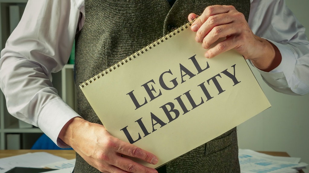 man holds a book about legal liability