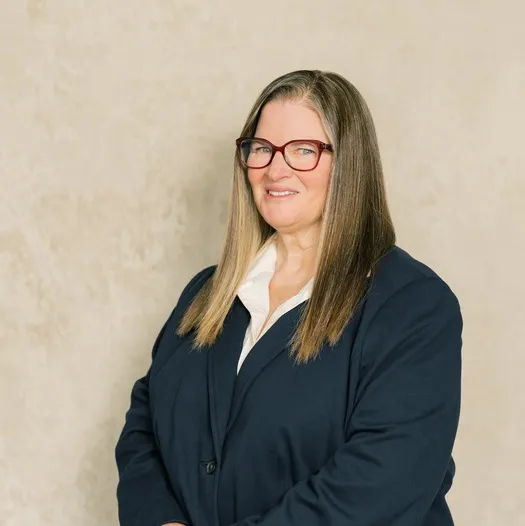 Professional woman with long straight hair wearing glasses and a navy blazer.
