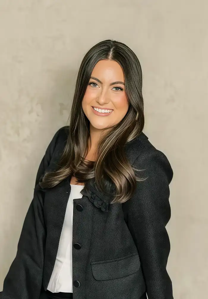 Professional portrait of a smiling woman with long dark hair wearing a black blazer and white blouse.