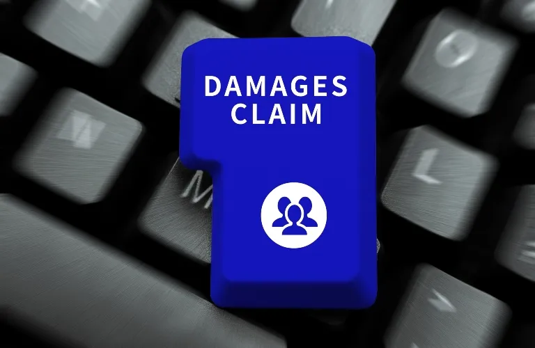 Blue keyboard key with white text "DAMAGES CLAIM" and a group of people icon, on gray keyboard.